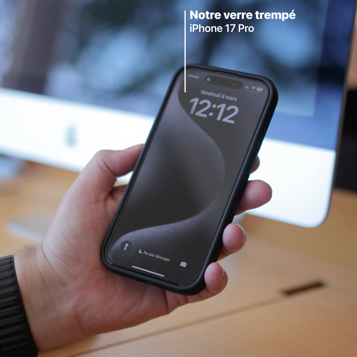 Téléphone tenu en main devant un écran d'ordinateur, écran protégé par le verre trempé